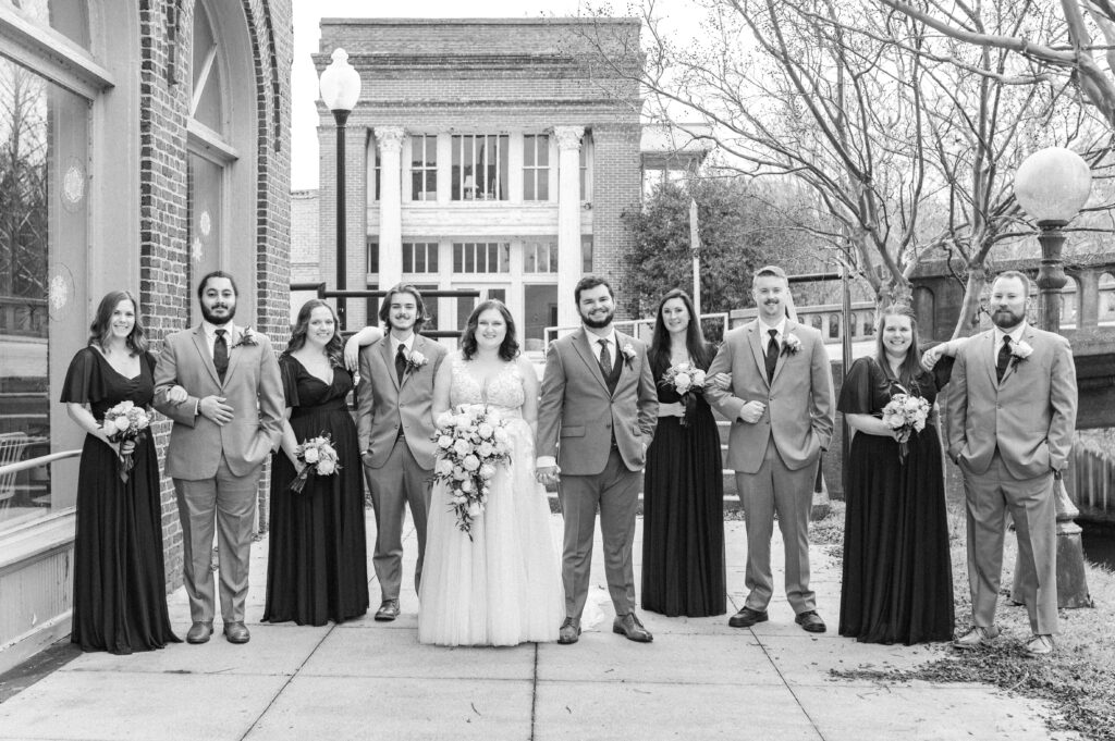 bride and groom with wedding party smiling