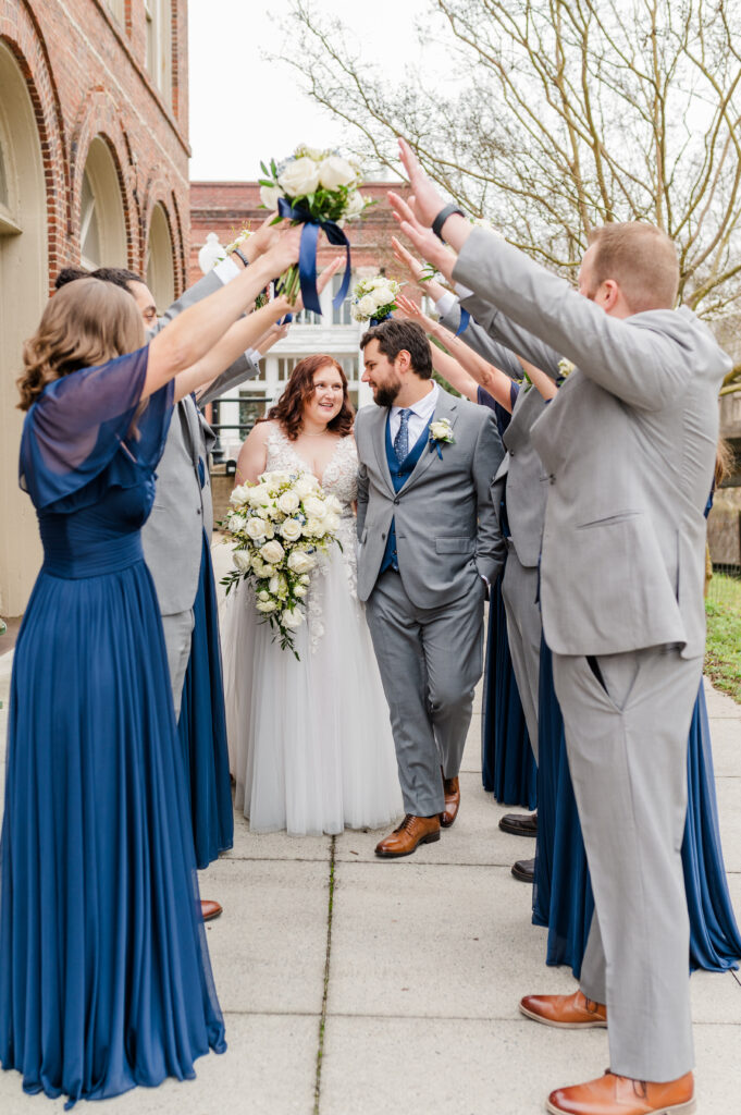 bride and groom with wedding party walking through hand tunnel