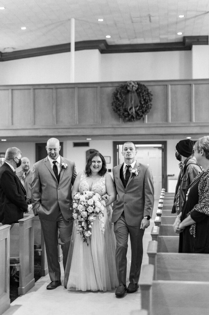 bride walking down aisle with brothers