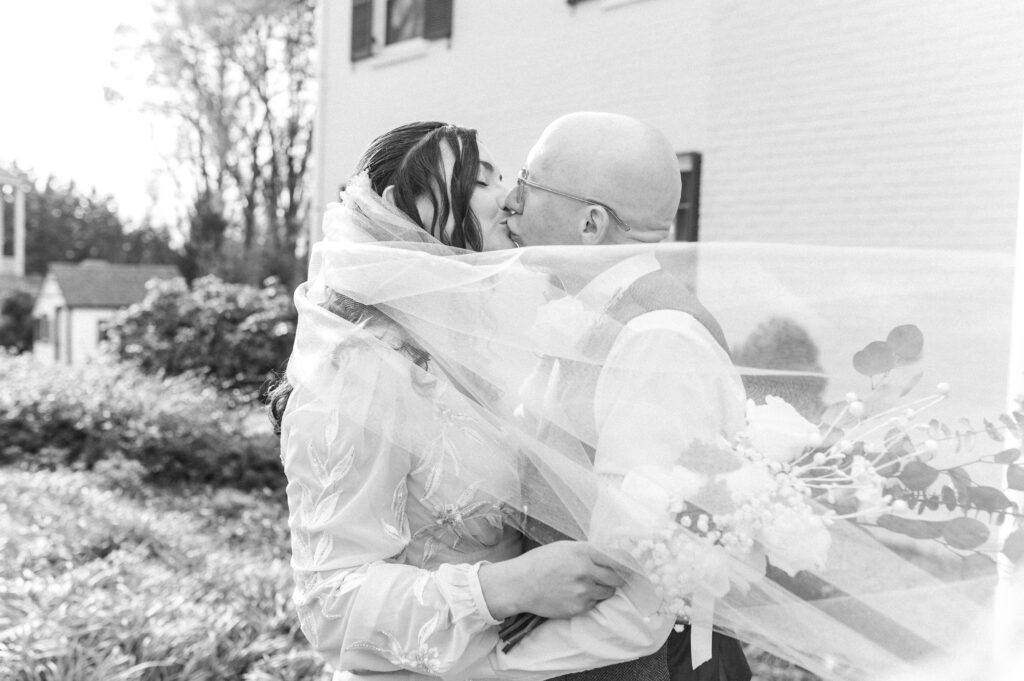 bride and groom kissing with veil