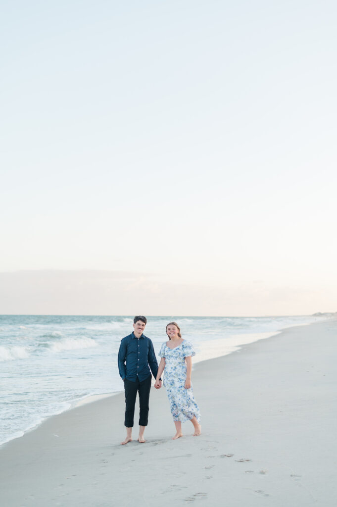 couple smiling at camera holding hands at topsail beach